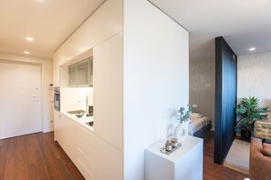 A modern kitchen with white cabinetry, a built-in oven, and a large mirror above the countertop. - Porto Gallery District Escape | Central Retreat (Porto)