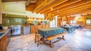 Una cocina amplia con vigas de madera, un comedor con mesa y sillas, y una sala de estar con sofá y chimenea.