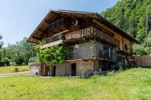 A rustic wooden house with a stone foundation, a balcony, and a staircase leading to an upper level. - Chalet du Vorger Ski – Spacious Mountain Retreat for Groups (villard sur doron)