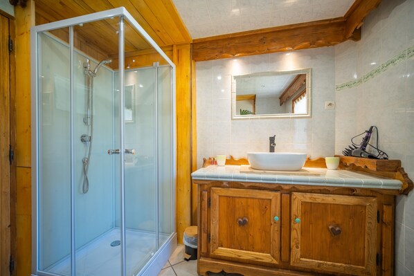 Un baño con cabina de ducha de vidrio, tocador de madera y espejo sobre el lavabo.