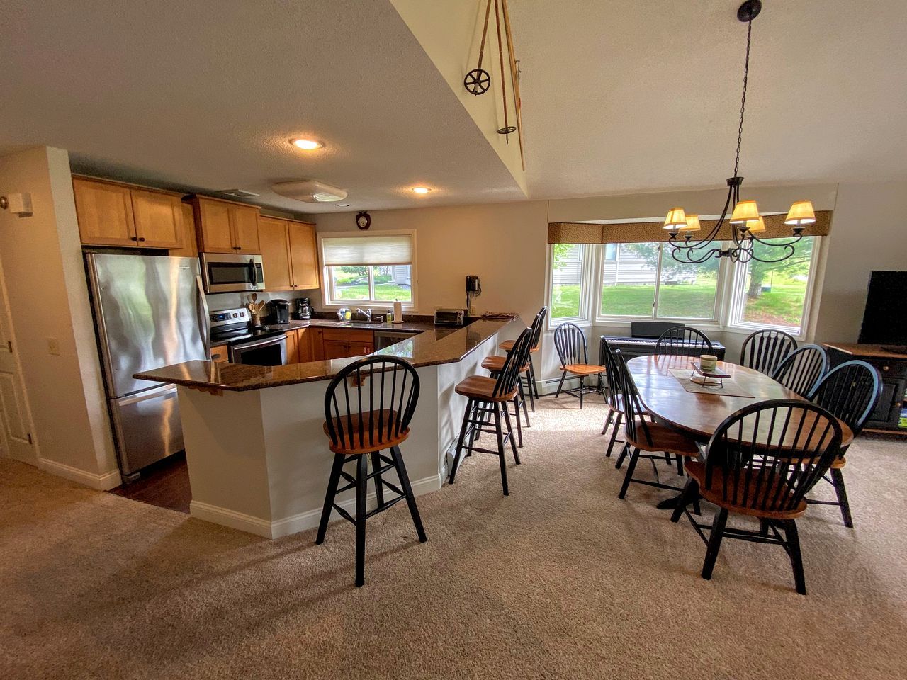 A kitchen with a central island, dining chairs, and a chandelier.