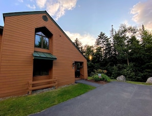 Een houten chalet met een schuin dak, een veranda en een verharde oprit.