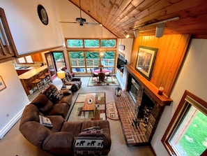 A spacious living room with a fireplace, a dining area, and a view of the outdoors. - Ski Cabin Rental Ideal for a Mount Washington Vacation (Carroll)