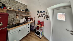 A compact kitchen with a stone wall, a red refrigerator, a sink, and a small window. - Fiberglass Geodesic Dome on a Hundred Acres of Private Woodlands near Lake Sinclair, Georgia (Milledgeville)