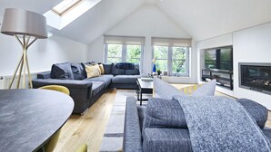 Una sala de estar moderna estilo loft, con un amplio sofá modular, una mesa de comedor y una chimenea.