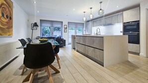 Una cocina moderna con una isla central, electrodomésticos integrados e iluminación colgante.