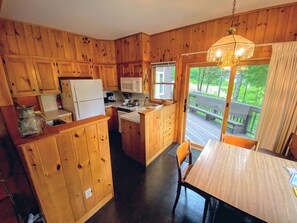 Eine Küchenzeile im Blockhausstil mit Holzschränken, einer zentralen Kochinsel und einem Esstisch mit Stühlen.