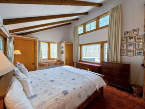 A bedroom with a large bed, wooden beams, a dresser, a desk, and a window with curtains. - Spacious Retreat for a White Mountains Vacation Getaway (Franconia)