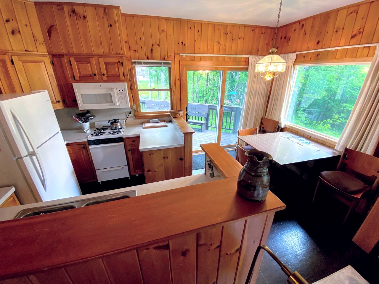 Ein Holzblockhaus-Interieur mit Küche, Essbereich und Blick ins Freie.