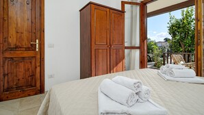 Ein Schlafzimmer mit Bett, Kleiderschrank und Blick durch ein großes Fenster.