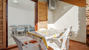 Eine Terrasse im Freien mit Tisch und Stühlen, einer Holztür und einer Steinwand.