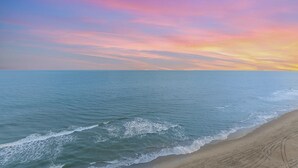 Ein Strand mit freiem Blick auf den Ozean und einem Sonnenuntergangshimmel.