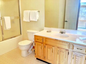 Une salle de bain avec des toilettes, une douche et des meubles en bois.