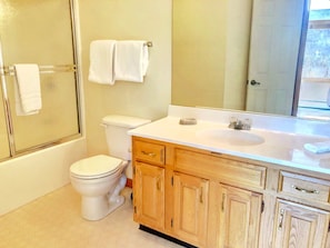 Ein Badezimmer mit Toilette, Dusche und Holzschränken.