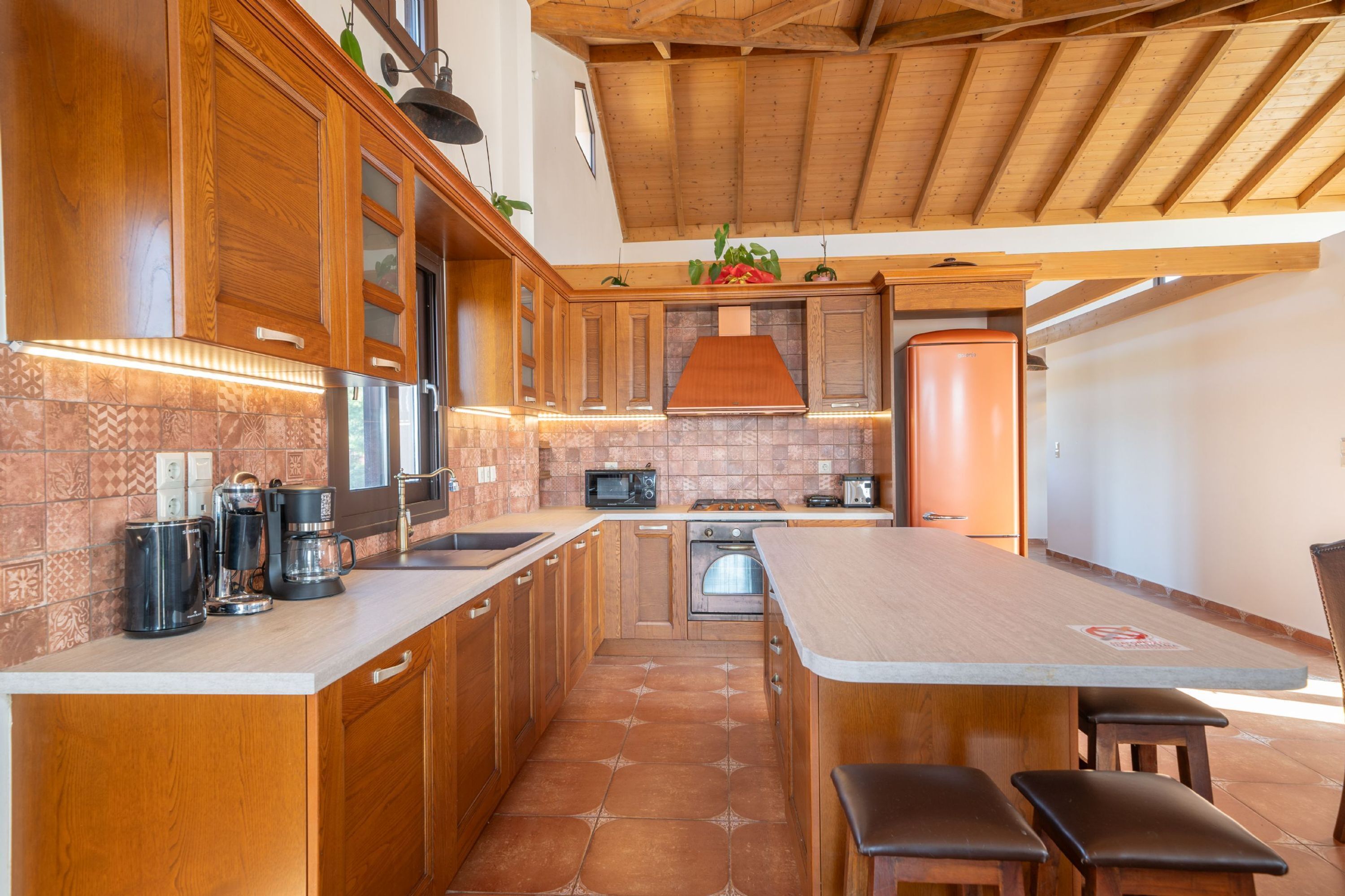 A kitchen with wooden cabinets, a large island, and a tiled backsplash.
