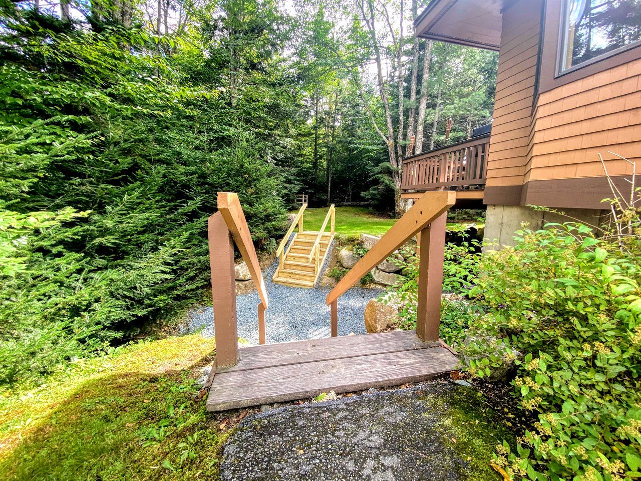 A wooden staircase leading to a deck with a view of a forested area.