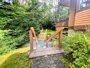 A wooden staircase leading to a deck with a view of a forested area. - Modern Cabin Rental Perfect for a Luxury Ski Vacation near Mount Washington (Carroll)