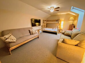 Ein gemütliches Zimmer mit einer Couch, einem Sessel, einem Etagenbett und einem Deckenventilator.