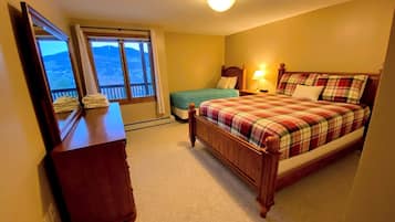Une chambre à coucher avec un lit, une commode, une fenêtre donnant sur un beau paysage et un luminaire au plafond.