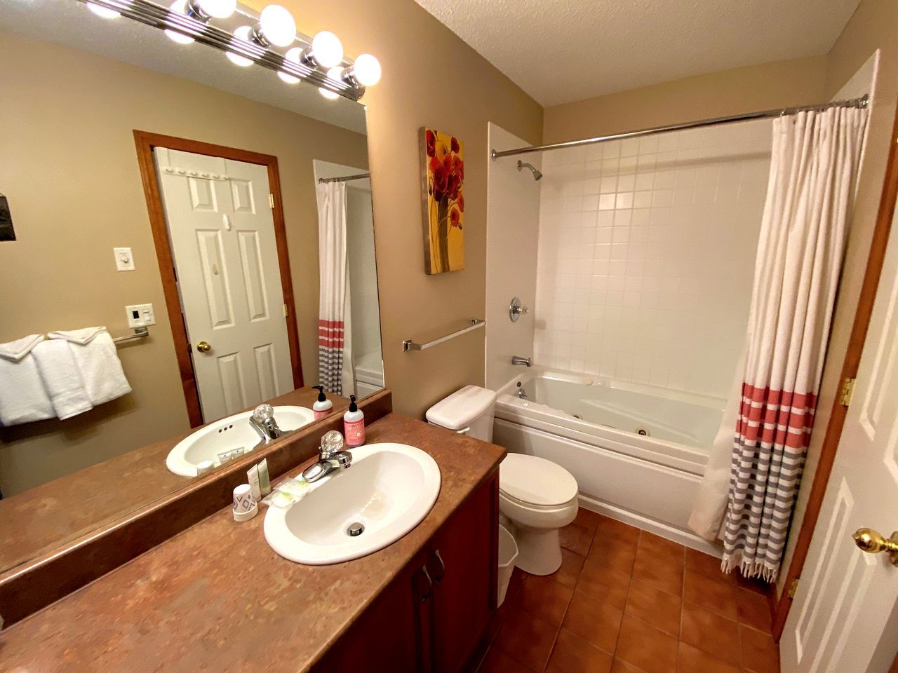 Une salle de bain avec deux lavabos, des toilettes, une baignoire et un rideau de douche.