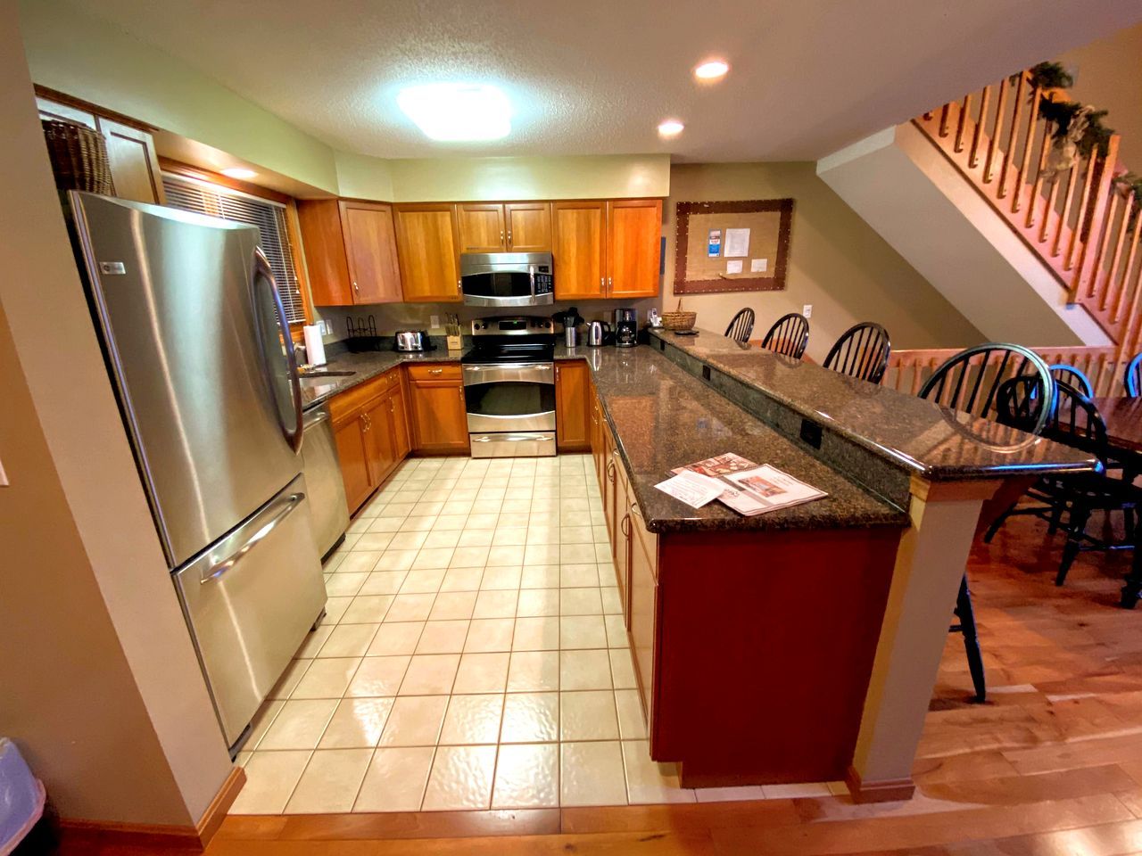 A kitchen with a refrigerator, microwave, stove, and wooden cabinets.
