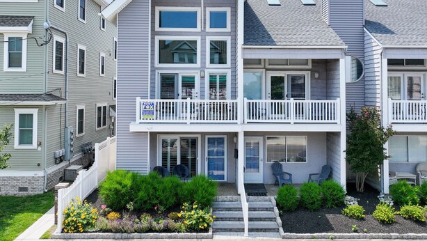 A two-story house with a balcony, a front porch, and a small garden area.