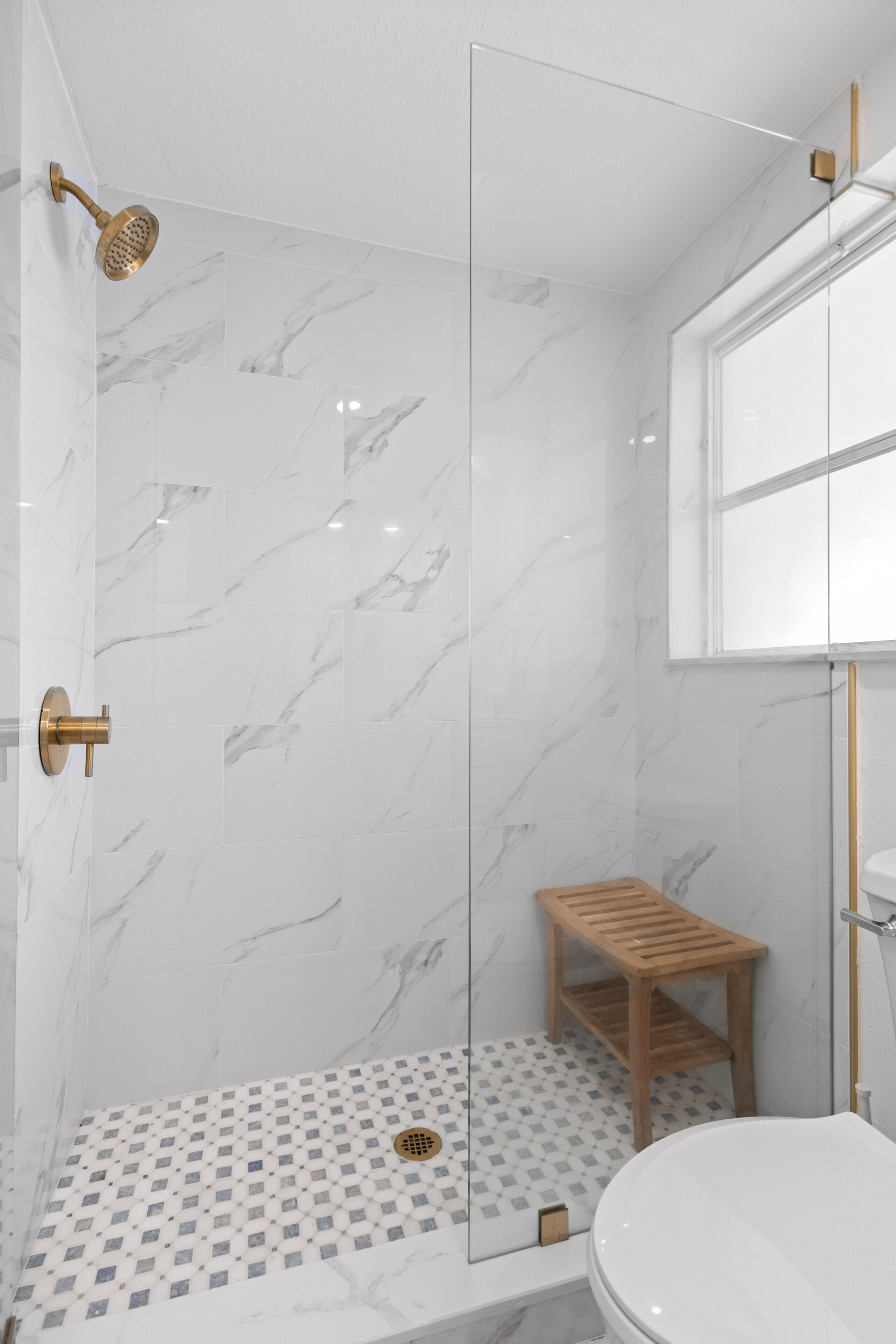 A modern bathroom with a shower, toilet, and a wooden shelf.