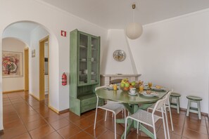 A dining area with a green table and chairs, a green cabinet, and a fire extinguisher on the wall. - #348 Madaleno Apartment | Cozy Stay (Albufeira)