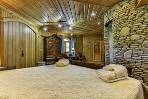 Ein Zimmer mit einem großen Bett, Holzwänden, einer Steinwand und einem Holzschrank.