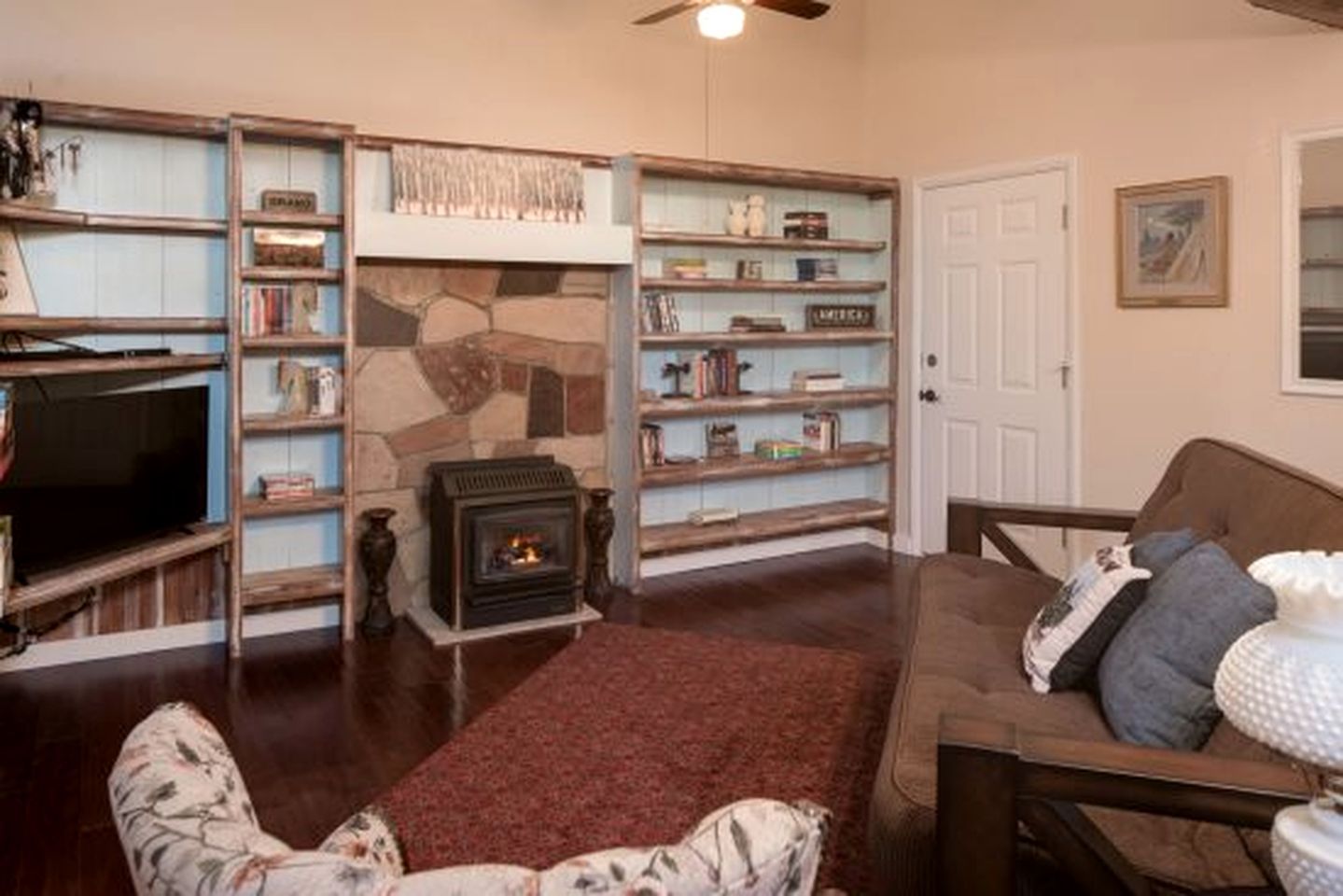 A cozy living room with a fireplace, bookshelves, a television, and a comfortable seating area.