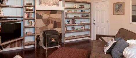 A cozy living room with a fireplace, bookshelves, a television, and a comfortable seating area.
