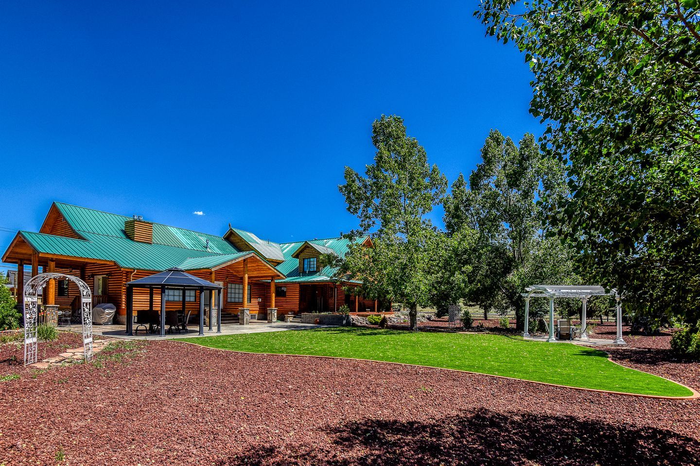 A lodge with a green roof, covered patio, and a gazebo.
