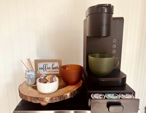 Una cafetera con portavasos, un bol de aperitivos y un letrero que indica barra de café.