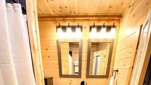 Un baño de cabaña de madera con dos lavamanos, un espejo y una cortina de ducha.