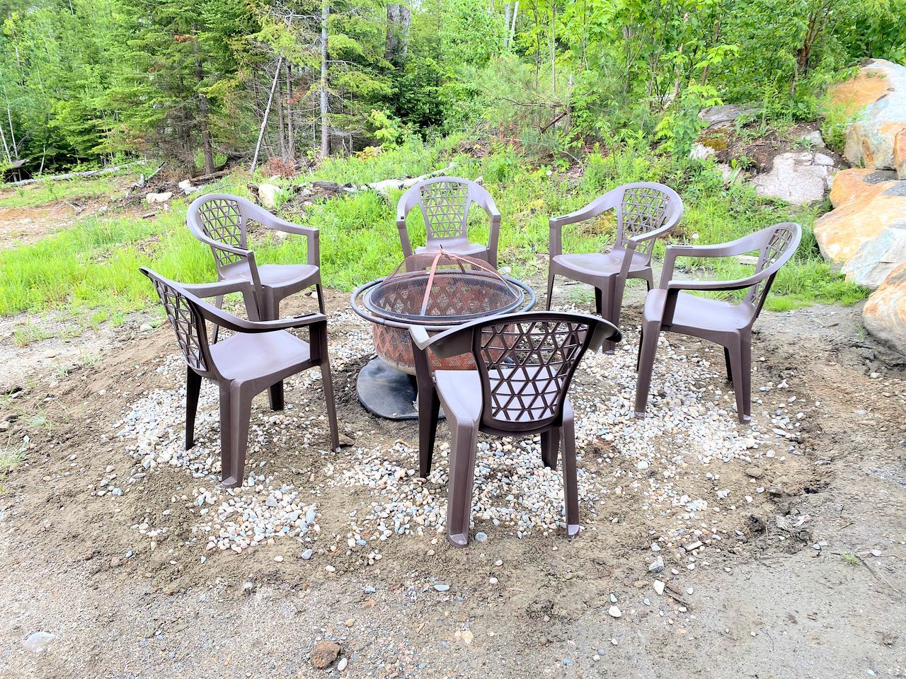 A table with four chairs in an outdoor setting with a natural backdrop.