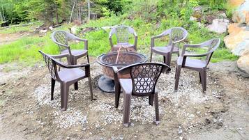 A table with four chairs in an outdoor setting with a natural backdrop.