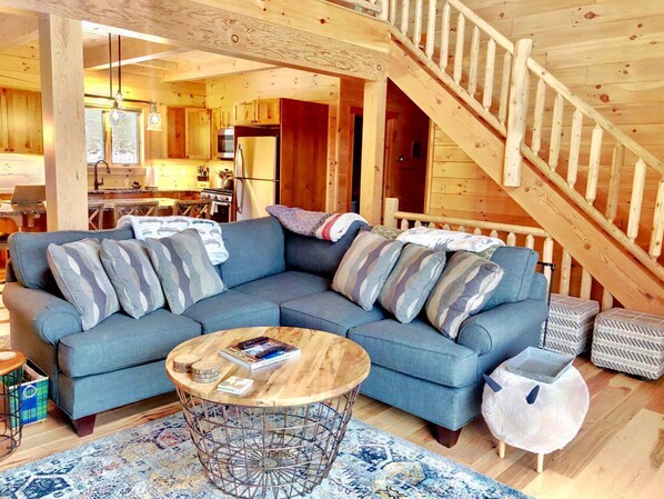 A cozy living room with a sectional sofa, a coffee table, and a staircase.