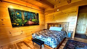Un dormitorio de cabaña de madera con cama, banco y un cuadro de un bosque.
