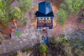 An aerial view of a building with a dark roof, multiple windows, and a deck area. - Contemporary Coziness Cabin in Hochatown, OK (Hochatown)