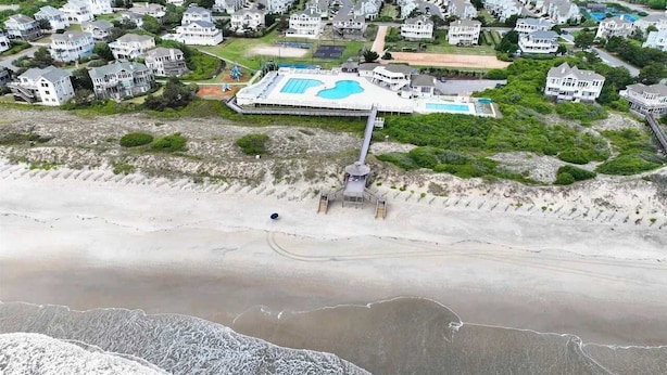 Ein Luftbild einer Küstenwohngegend mit Häusern, einem Swimmingpool und einem Strand.