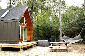 A cabin with a wooden deck, a hammock, and a picnic table. - Gorgeous Cozy Cabin in Montgomery, Texas (Montgomery)