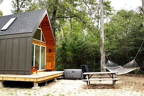 A cabin with a wooden deck, a hammock, and a picnic table. - Gorgeous Cozy Cabin in Montgomery, Texas (Montgomery)