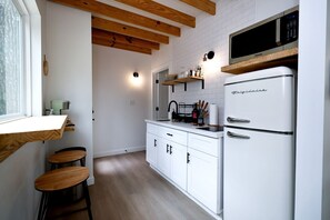 Une cuisine moderne avec des armoires blanches, un réfrigérateur en acier inoxydable, un four à micro-ondes et un plafond en bois.
