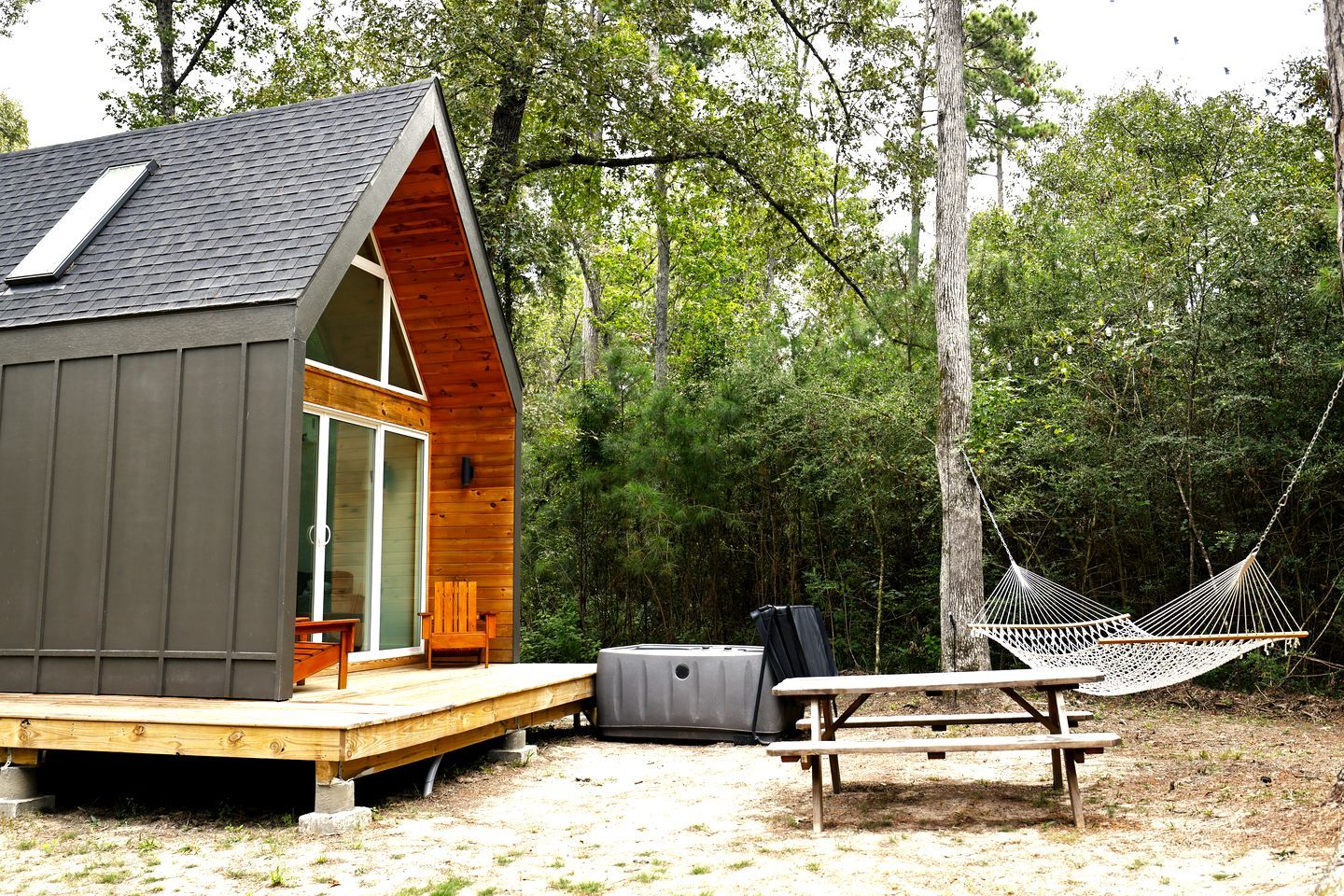 A cabin with a wooden deck, a hammock, and a picnic table.