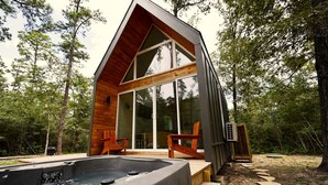 Uma cabana moderna com hidromassagem, deck de madeira e grandes portas de vidro.
