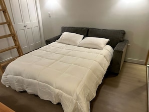 A bed with a white duvet, a dark headboard, and a wooden ladder. - Gorgeous Cozy Cabin in Montgomery, Texas (Montgomery)