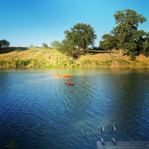 Un lago tranquillo con kayak, un molo e alberi sullo sfondo.