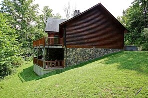 Eine Blockhütte mit Steinunterbau, einem Balkon und einem Rasen.