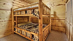 Ein Etagenbett mit gemustertem Bettbezug in einem Holzhütten-Schlafraum.