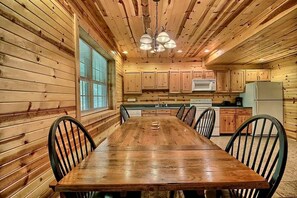 A wooden interior with a dining table, chairs, a kitchen area, and a window with blinds. - Group Spacious Cabin with Hot-Tub and Picnic Areas in Ohio (Rockbridge)